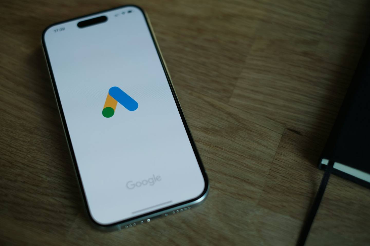 A phone on a wooden desk showing the Google Ads logo