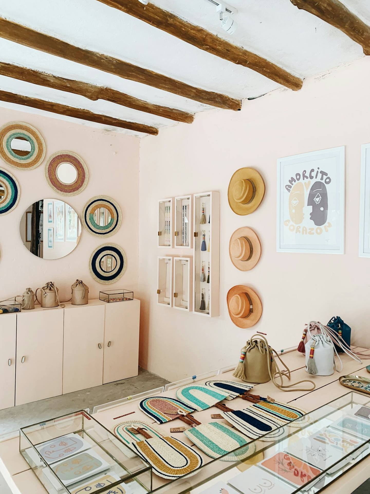 A bright boutique wall with hats and round mirrors