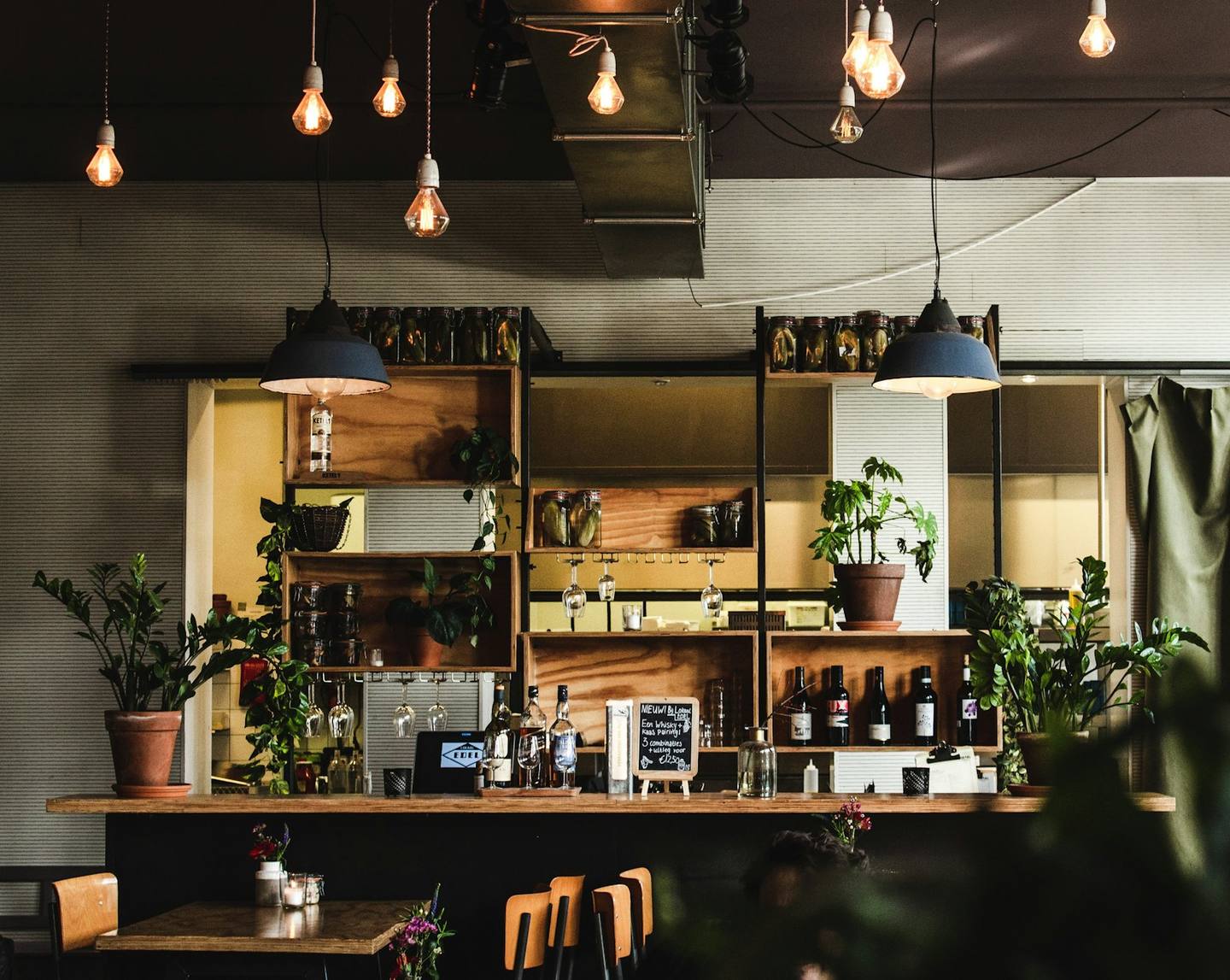 A warm café bar filled with plants and hanging lights